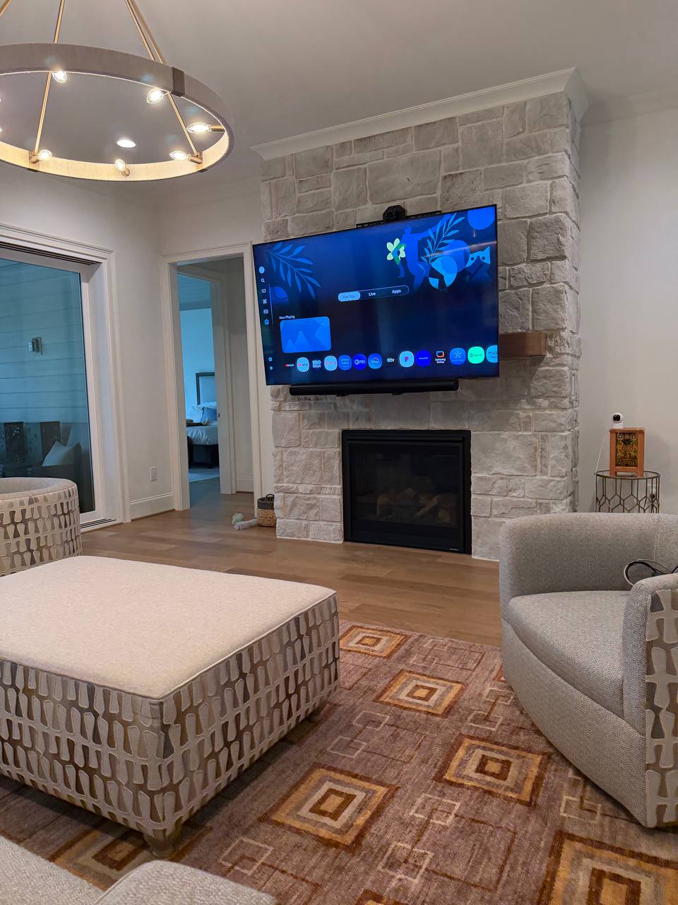 Motorized pull-down mount with LG TV and Sonos soundbar at stone fireplace in Roxboro, NC