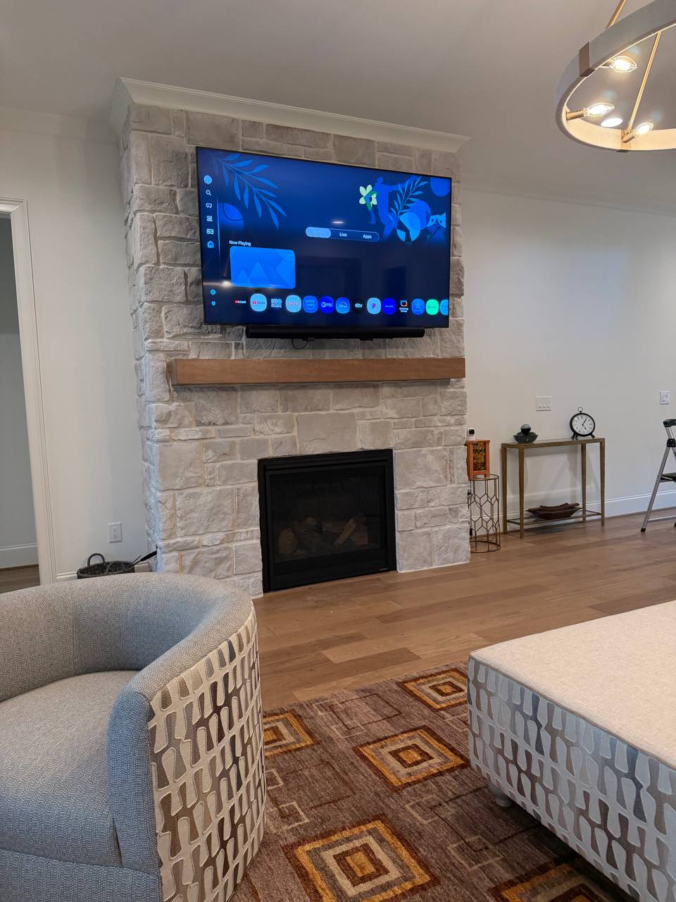 75-inch LG TV on motorized pull-down mount with Sonos soundbar above stone fireplace in Roxboro, NC